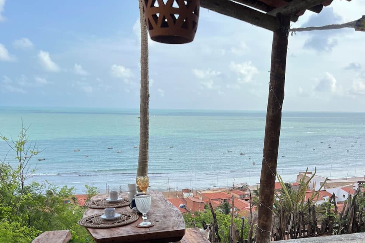 Un área de comedor al aire libre con vista al mar y edificios en el fondo.
