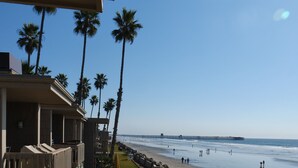 A beachfront hotel with a view of the ocean and a pier in the distance. - Tranquil 2 Bd Oceanfront Condo in charming Oceanside with WiFi, fitness room. (Oceanside)