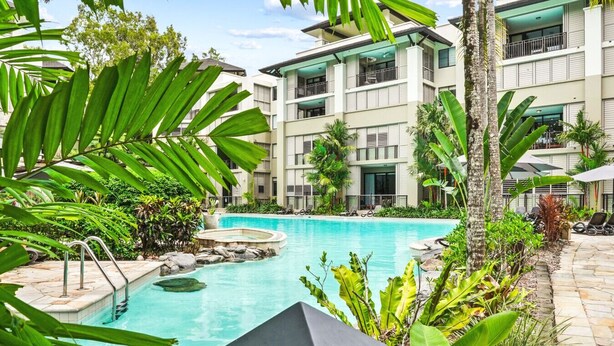 A modern hotel with a pool surrounded by lush tropical plants. - Luxury Studio in Palm Cove Resort | Steps to Beach & Pools (Palm Cove)