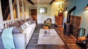 A cozy living room with a sofa, a small table, a chair, a fireplace, and a staircase. - Charming self-catering cottage in a Plus Beau Village, near Pompadour. (Ségur-le-Château)