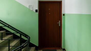 Une porte en bois avec une plaque portant un numéro, une main courante en métal et un mur aux couleurs verte et blanche.