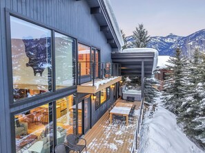 Ein modernes Gebäude mit großen Fenstern, einer Holzterrasse und einem Whirlpool.