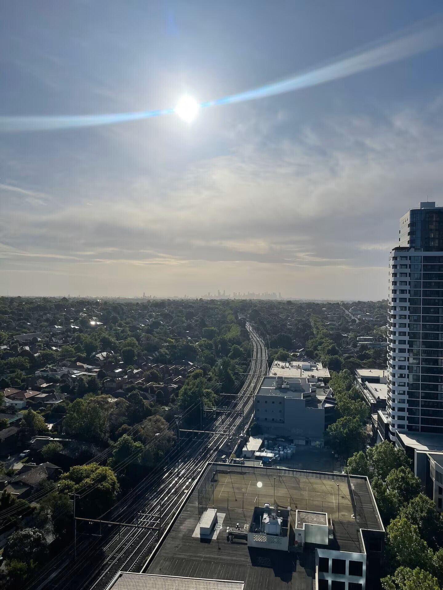 Vue aérienne d’une ville, avec un immeuble de grande hauteur qui domine le paysage, une voie ferrée et les quartiers résidentiels environnants.