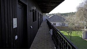 Un balcón techado con vistas a una casa y árboles.
