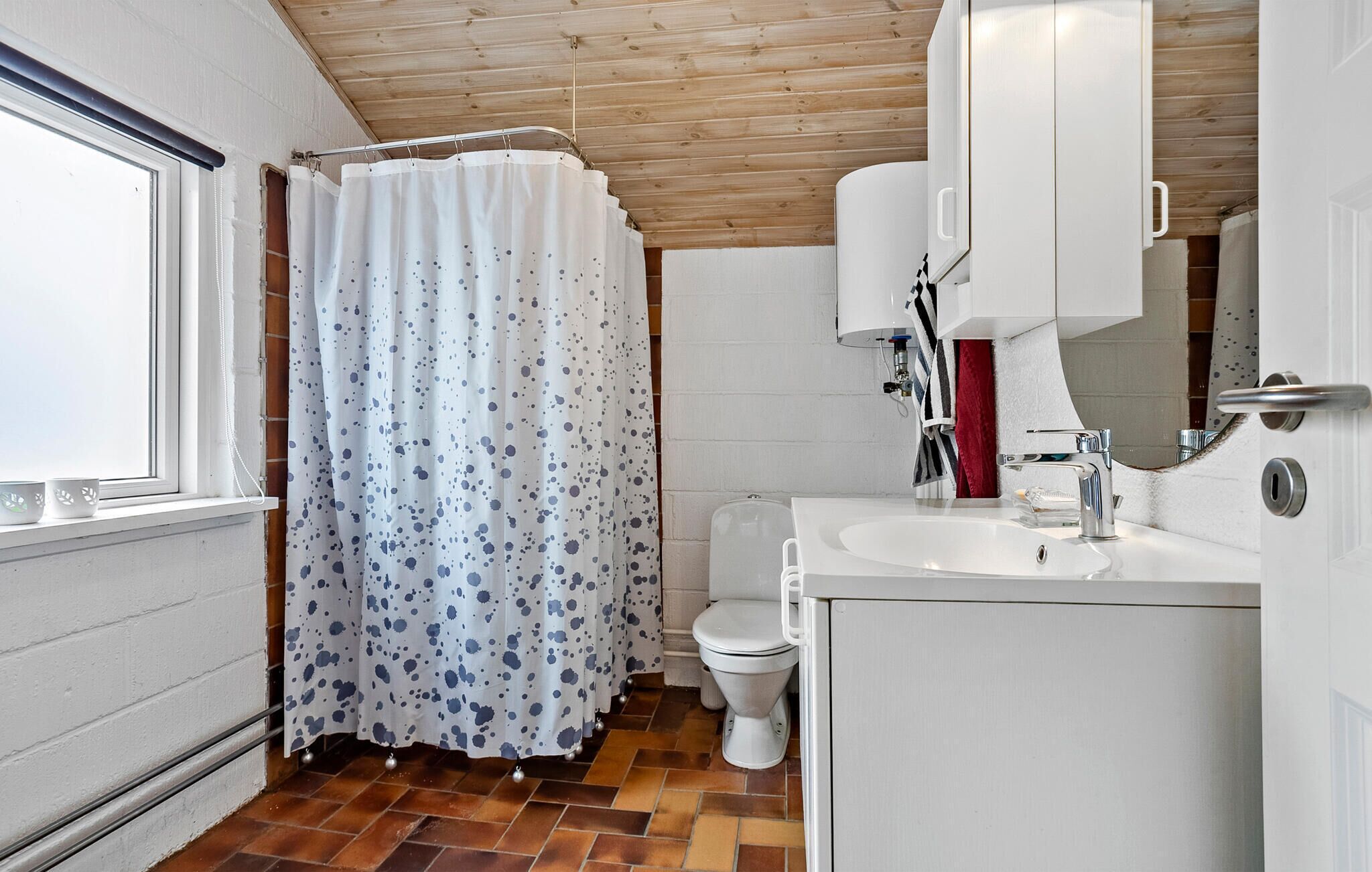 Et badeværelse med badeforhæng, toilet, vask og spejl.