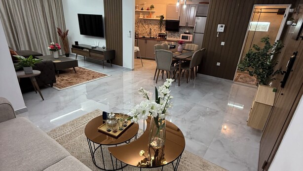 A modern living room with a sofa, coffee table, and a dining area with chairs and a table.