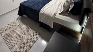 A bedroom with a bed, bedside table, and a TV mounted on the wall.