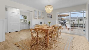 A dining area with a wooden table and chairs, a chandelier, and a view of a pool and outdoor area.