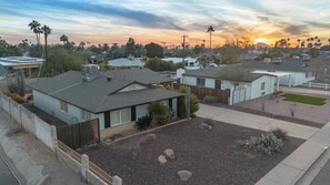 Zona residencial con casas, cielo despejado y un atardecer.