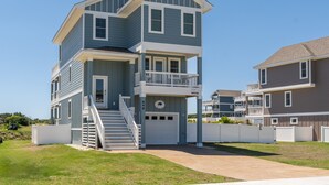 A two-story residential building with a front porch, a staircase, and a garage. - The Blue Buffalo: Private Pool, Resort Amenities (Corolla)