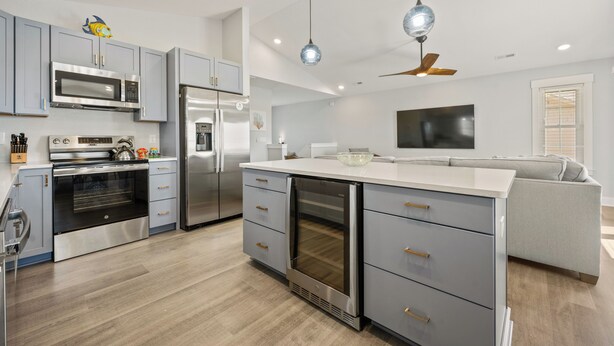 A modern kitchen with stainless steel appliances, grey cabinetry, and a central island. - The Blue Buffalo: Private Pool, Resort Amenities (Corolla)