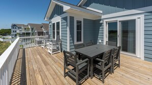 A deck with a table and chairs, overlooking a residential area with houses. - The Blue Buffalo: Private Pool, Resort Amenities (Corolla)