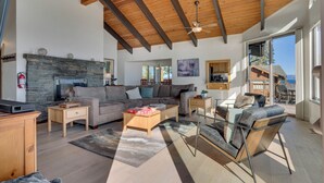 A spacious living room with a stone fireplace, a sofa, a coffee table, and a glass dining table.