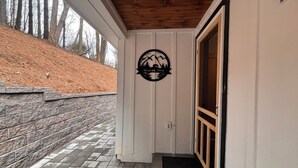 Un porche cubierto con un muro de piedra, una puerta de madera y un logo en la pared.