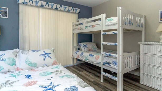 Habitación con literas de temática náutica, con estampados de estrellas de mar y corales en la ropa de cama.
