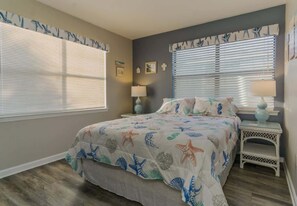 Een slaapkamer met een bed, twee nachtkastjes en een raam met jaloezieën.