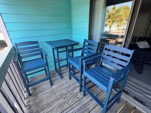 A porch with a blue table and chairs, wooden flooring, and a view of the outside.