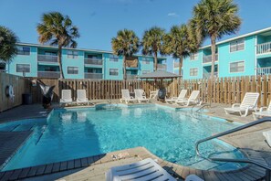 A swimming pool with lounge chairs and a wooden fence.