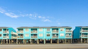 Une rangée de bâtiments turquoise au bord de la mer, dotés de balcons, portant l’inscription « Lani Kai 728 ».