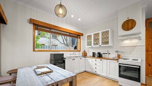Una cucina moderna con mobili bianchi, un tavolo da pranzo in legno e un'ampia finestra.