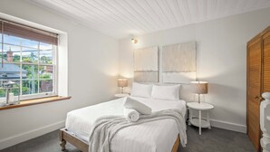 Una camera da letto con un letto grande, una finestra con tende, un comodino con una lampada e un armadio in legno.