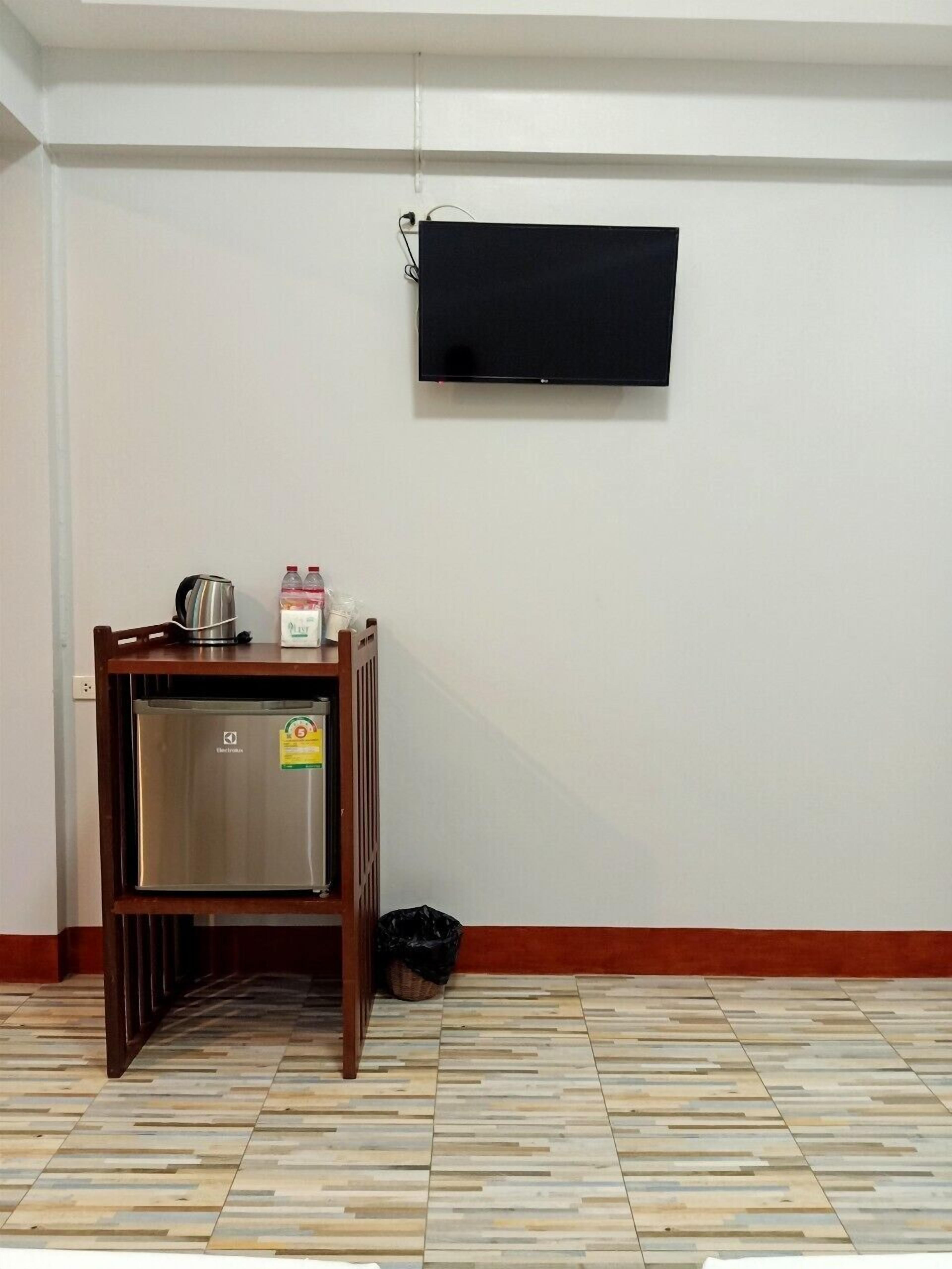 Une chambre dotée d’une kitchenette, d’un téléviseur à écran plat fixé au mur et d’un sol carrelé.