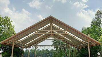 Un pavillon abrité, doté d’une moquette verte et de chaises, qui offre une vue sur une étendue d’eau.