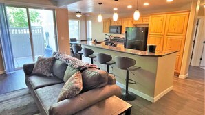 A modern kitchen with wooden cabinets, a central island with bar stools, and a built-in microwave.