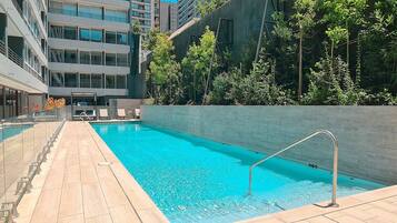 Relax by the rectangular pool surrounded by a tiled deck and lush greenery.