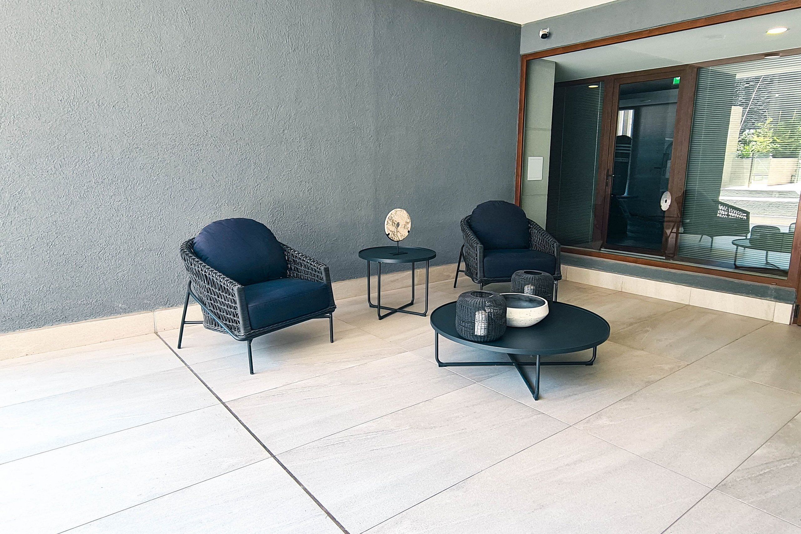 A modern indoor seating area with two wicker chairs, a small round table, and a coffee table with decorative items.