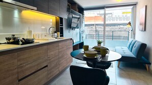 Una cuina moderna amb zona de menjador, un sofà i una finestra gran amb vistes a l'exterior.
