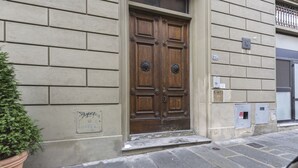 Un edificio con una puerta doble de madera, una planta en maceta y un acceso adoquinado de piedra.
