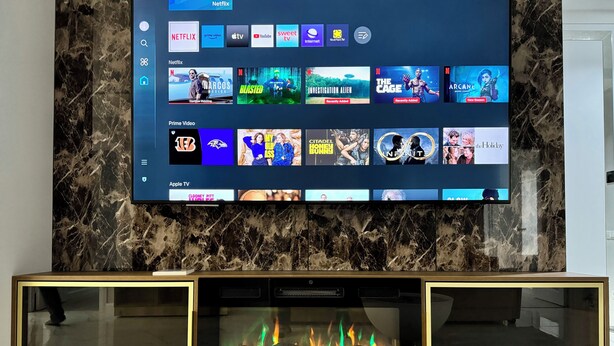 Ein Flachbildfernseher, der an einer Marmorwand angebracht ist und verschiedene Streaming-Dienste anzeigt.