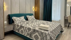 Ein modernes Schlafzimmer mit einem türkisfarbenen Bett, gemusterten Betttextilien und einem Holzkopfende.