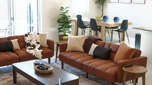 Ein Wohnzimmer mit zwei braunen Sofas, einem Couchtisch und einem Essbereich mit Tisch und Stühlen.
