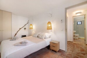 A bedroom with a bed, bedside table, and a view into the bathroom.