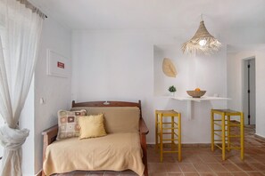 Une pièce comprenant un lit, un luminaire suspendu, une petite table avec un bol et une chaise.
