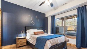 Un dormitorio con cama, mesita de noche y ventana con cortinas.