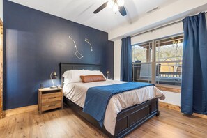 Un dormitorio con cama, mesita de noche y ventana con cortinas.