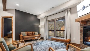Una sala de estar moderna con chimenea, un sofá y un ventanal grande.