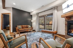 Una sala de estar moderna con chimenea, un sofá y un ventanal grande.