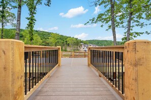 A wooden bridge with metal railings leading to a building with a sloped roof.