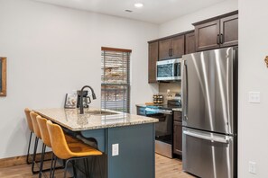 Una cocina con isla integrada, electrodomésticos de acero inoxidable y taburetes de madera.