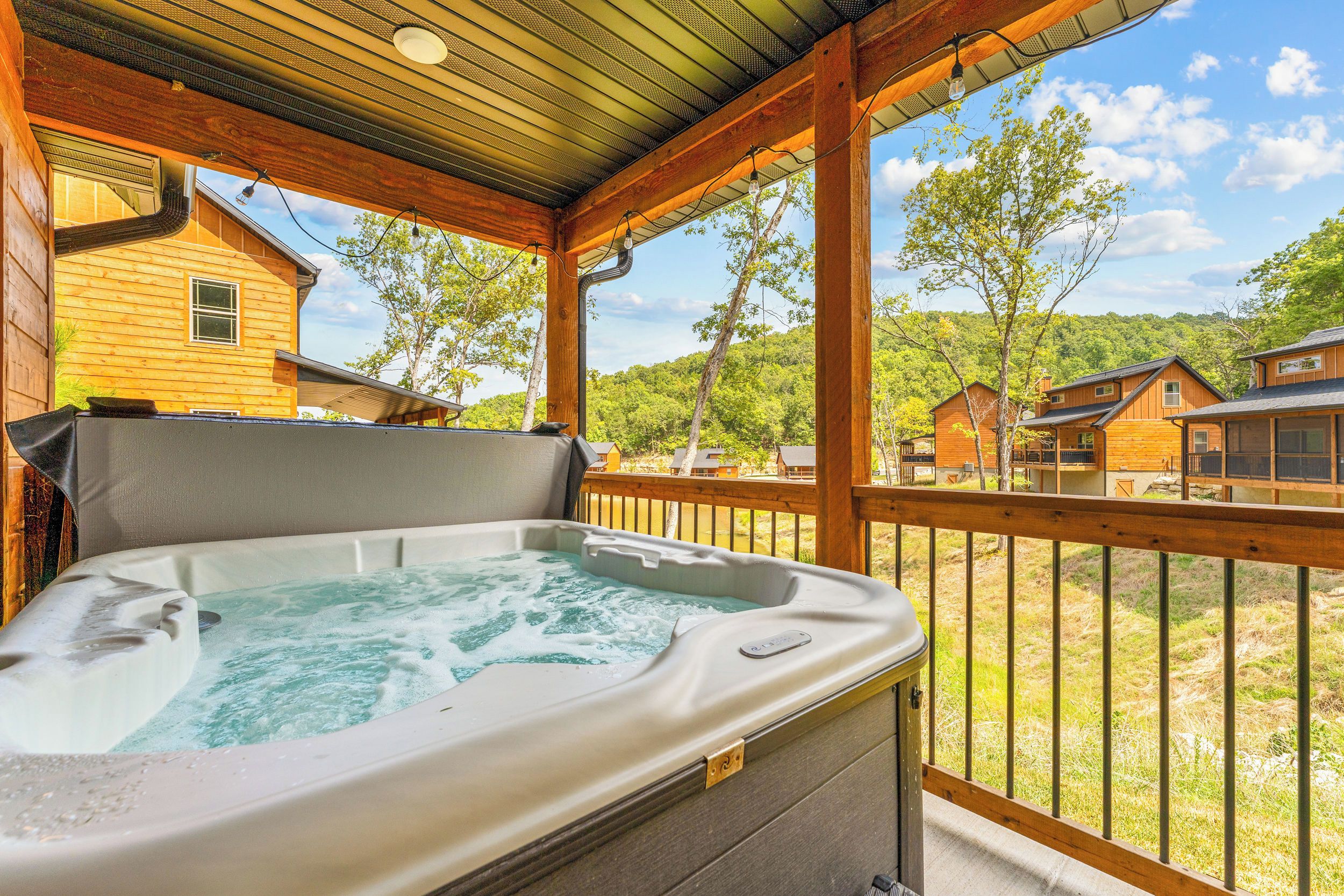 A hot tub on a wooden deck with a view of a forested landscape.