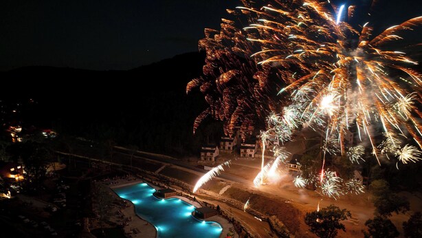 Vista aérea de un resort con piscina y un espectáculo de fuegos artificiales.