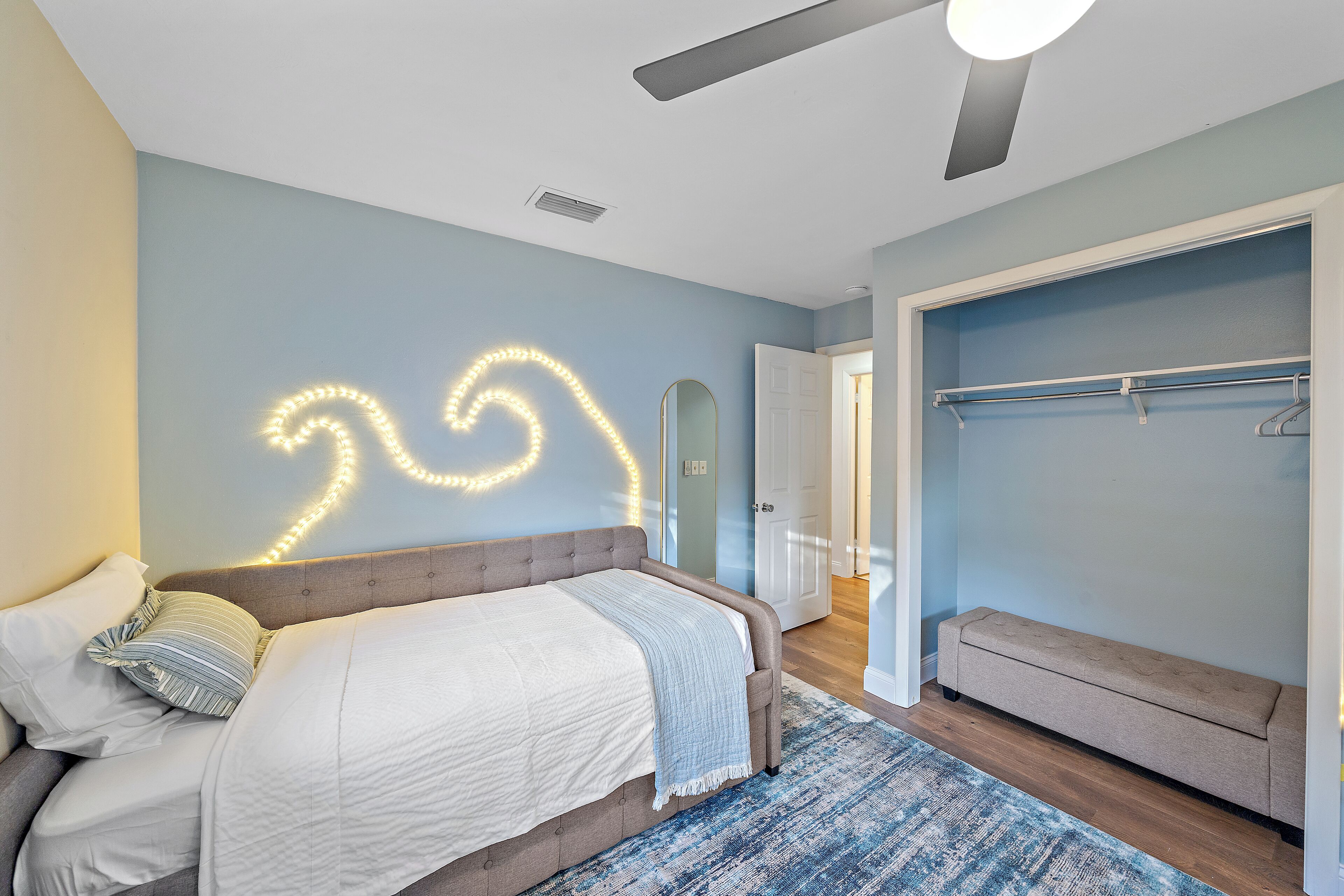 Une chambre à coucher avec un lit, un banc, une armoire et un miroir.