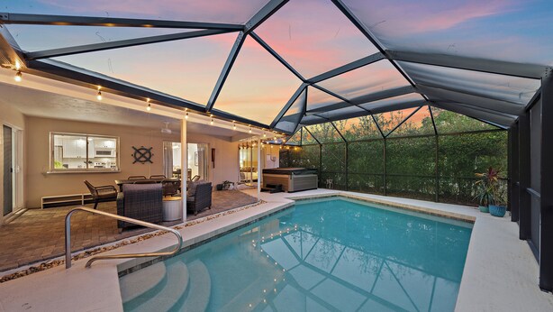 A swimming pool with a glass ceiling, outdoor seating, and a view of the surrounding trees. - Breezemont Bungalow | Private Heated Pool, Hot tub + Sauna (Sarasota)