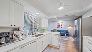 A modern kitchen with white cabinetry, a coffee machine, and a stainless steel refrigerator. - Breezemont Bungalow | Private Heated Pool, Hot tub + Sauna (Sarasota)