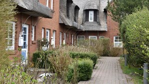 A row of brick houses with unique thatched roofs and a narrow pathway between them.