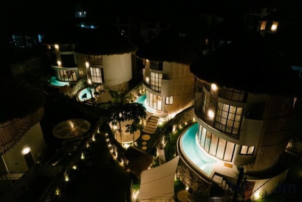 A multi-story building with a pool, outdoor lighting, and a circular structure. - Hillstone Luxury Village (Bali)
